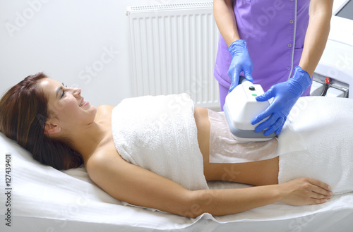 Pretty young woman getting cryolipolyse treatment in cosmetic ca photo