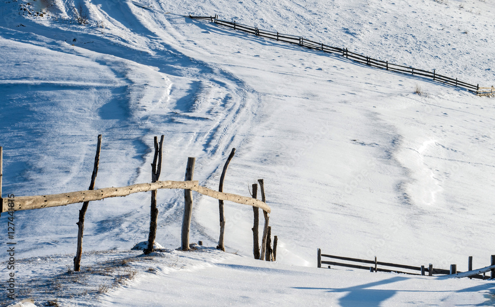 The fence in a pasture in the winter. Hills covered with snow. The fence in a pasture in the winter. Hills covered with snow.