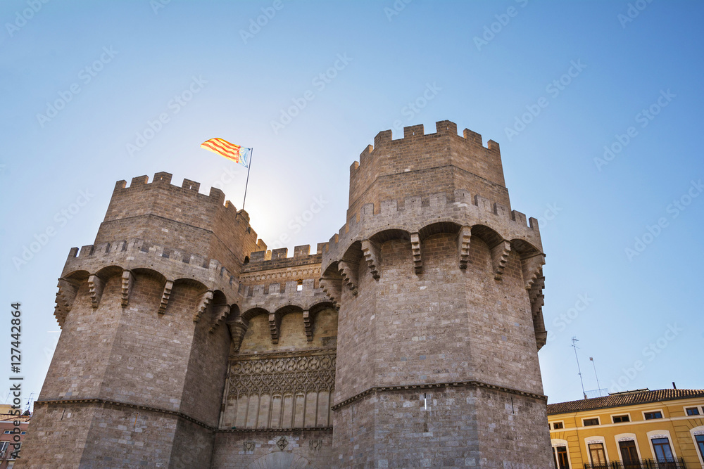 Exterior  facade of Serranos Gate or Serranos Towers, part of the ancient city wall of Valencia, Spain. Valencia flag flying from the top of the building.