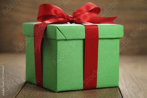 Fototapeta Naklejka Na Ścianę i Meble -  green paper gift box gift box with lid and red ribbon bow on wood table