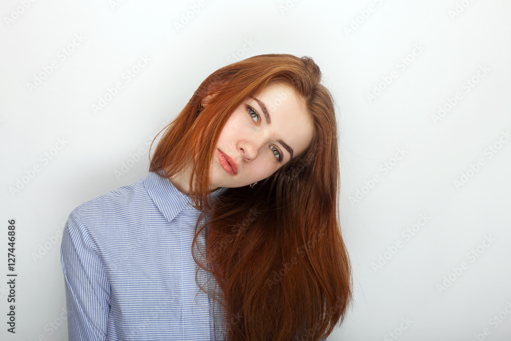 Young serious angry redhead beautiful woman in shirt portrait on a white background Young serious angry redhead beautiful woman in shirt portrait on a white background
