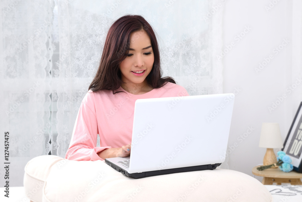 Asian girl with notebook in bedroom. Asian girl with notebook in bedroom.