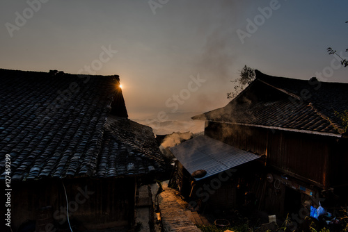 Sun rising behingtraditional Chinese minority houses