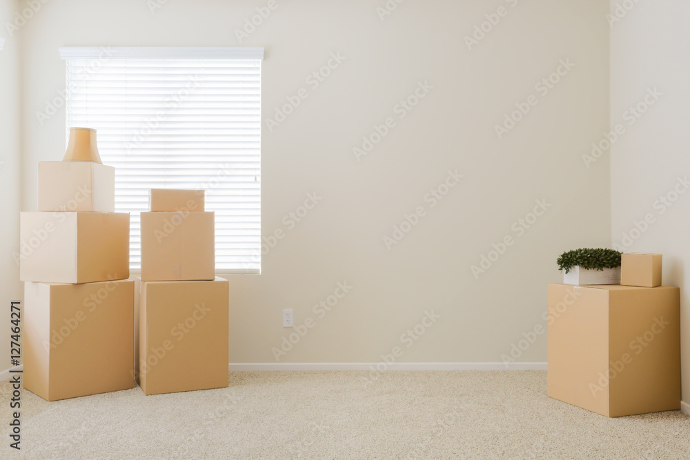 Fototapeta premium Variety of Packed Moving Boxes and Potted Plants In Empty Room with Room For Text.