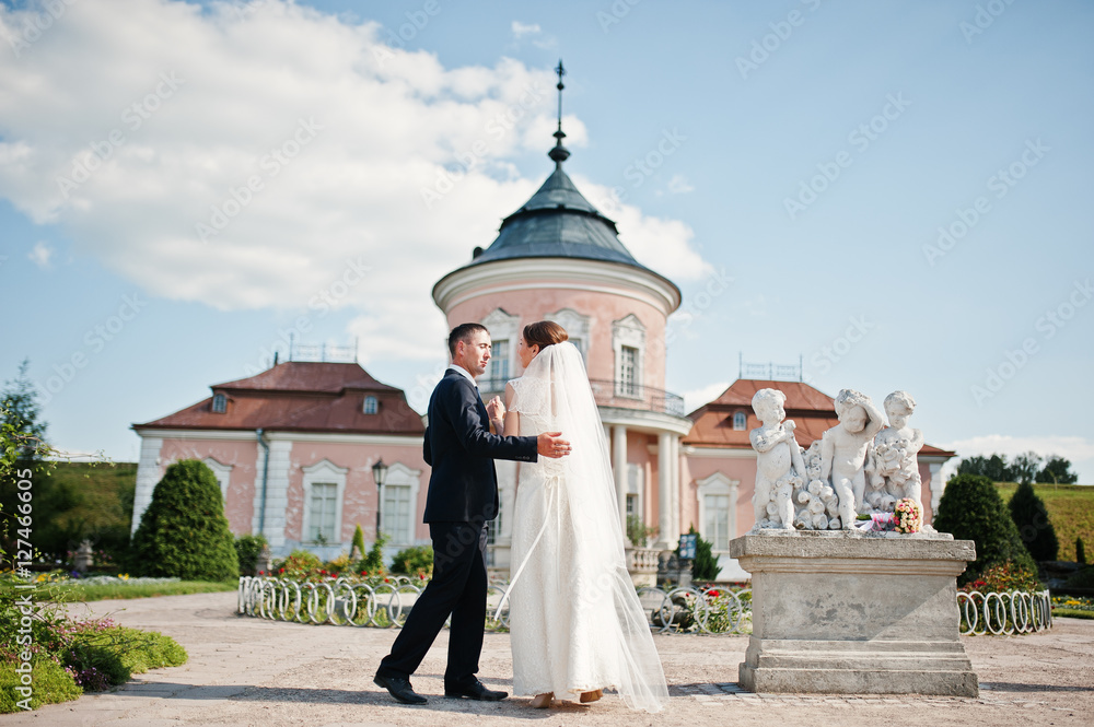 Wedding couple at yard of old mansion with monument of three boy