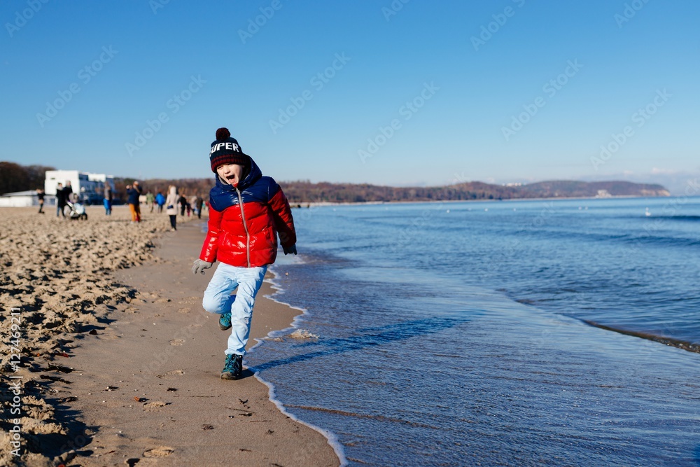 Happy little child boy running on the beach