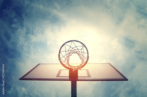 Basketball hoop on basketball court under blue sky with clouds