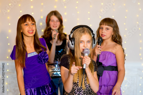 Group of happy girls singing on karaoke