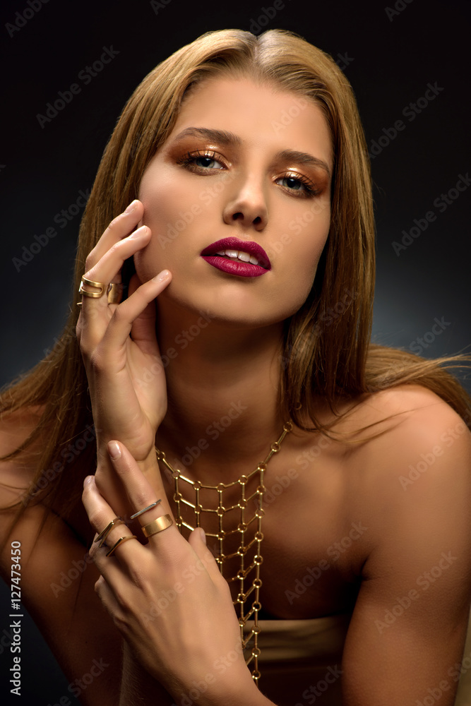 Obraz premium Fashion photo of attractive young blonde woman with styled make–up, long necklace and many rings on her fingers