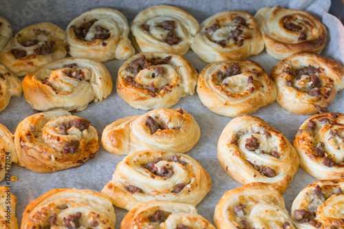 Puff pastry pizza rolls with minced beef on baking tray in oven.