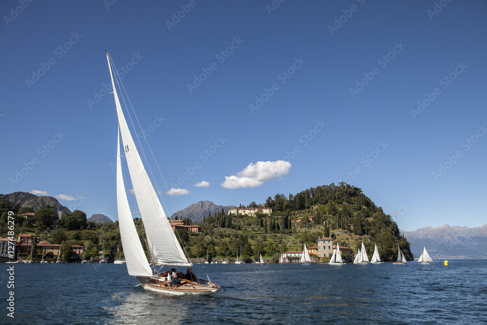 Obraz premium punta Serbelloni a Bellagio sul lago di Como con nuvole, riflessi nell'acqua e barche a vela