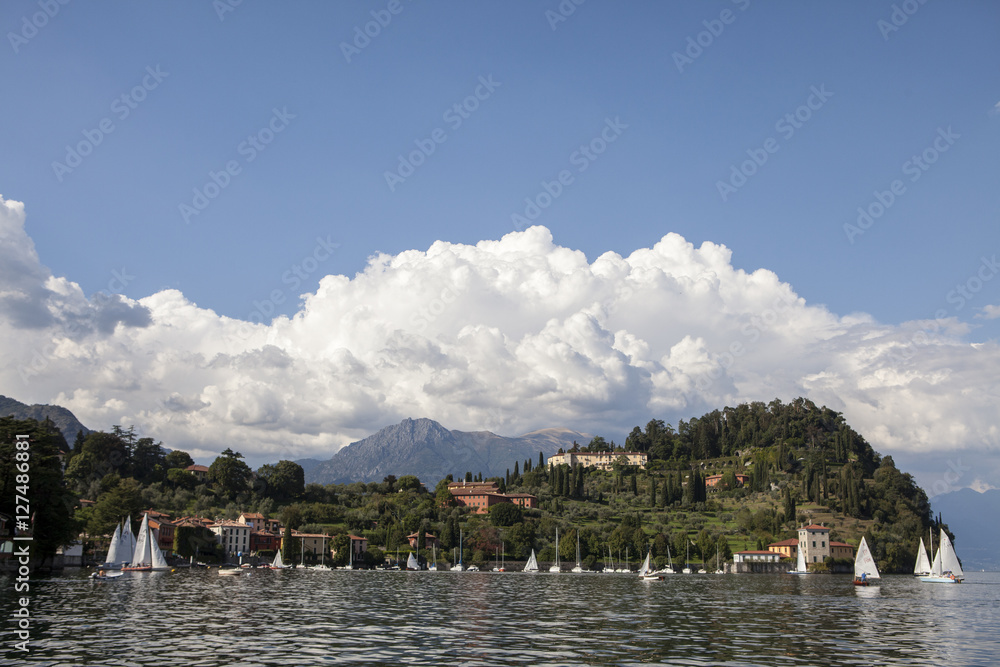 punta Serbelloni a Bellagio sul lago di Como con nuvole, riflessi nell'acqua e barche a vela