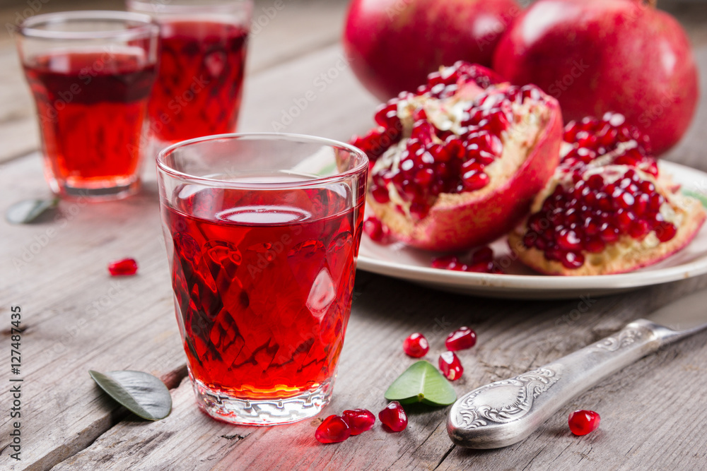 Whole and broken red ripe juicy pomegranates on rustic wooden unpainted table Whole and broken red ripe juicy pomegranates on rustic wooden unpainted table