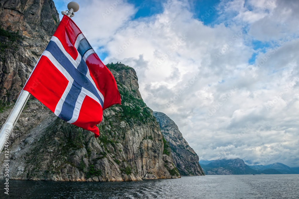 Fototapeta premium Norwegian flag against fjord mountains.
