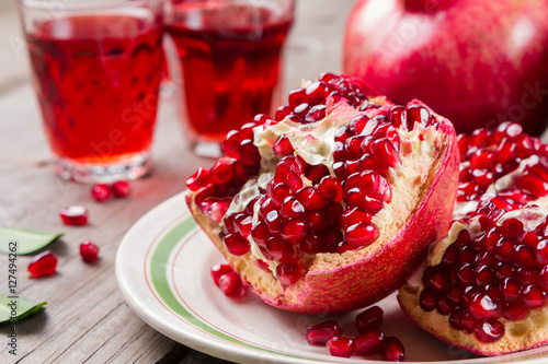 Whole and broken red ripe juicy pomegranates on rustic wooden unpainted table