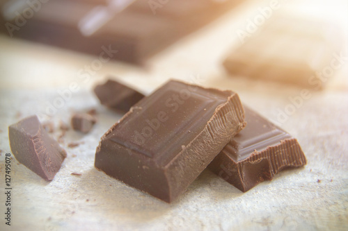 Some ounces of dark chocolate on white wooden table.