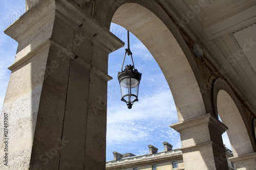 Traditional, old street lamp located on architectural arch of historical building in Paris.