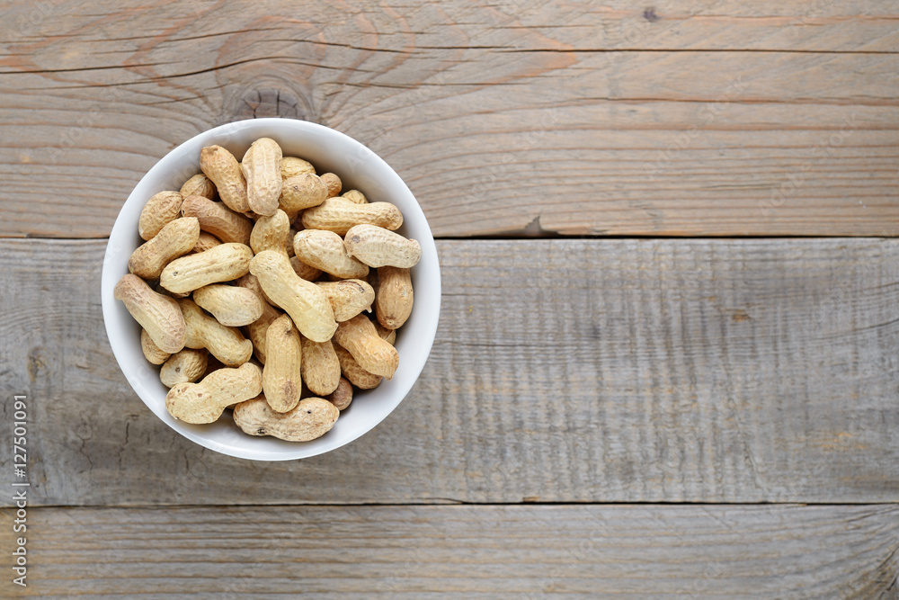 Roasted peanuts in bowl on wooden background Roasted peanuts in bowl on wooden background