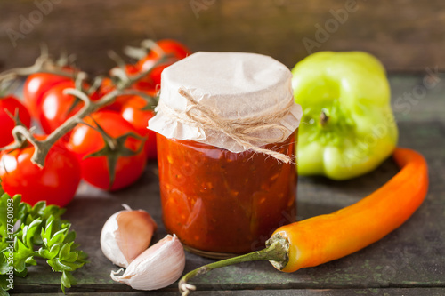 Fotografía tomato sauce adjika and vegetables on a table, selective focus