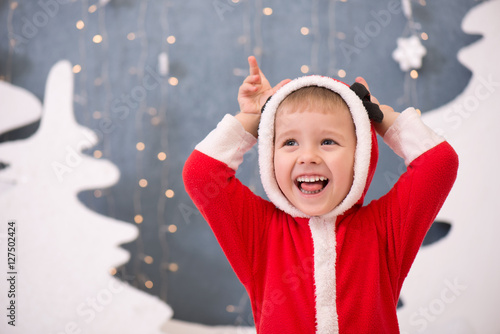 Очень веселый ребенок в рождественском костюме на новогоднем фоне