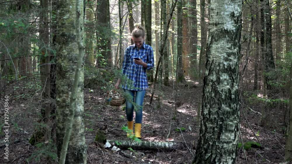 smiling lost mushroom picker woman holding cellphone with gps in forest smiling lost mushroom picker woman holding cellphone with gps in forest