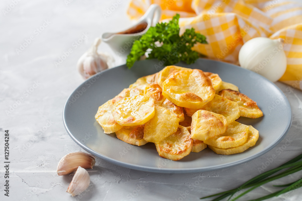 potatoes baked by slices in a plate on a table, selective focus potatoes baked by slices in a plate on a table, selective focus