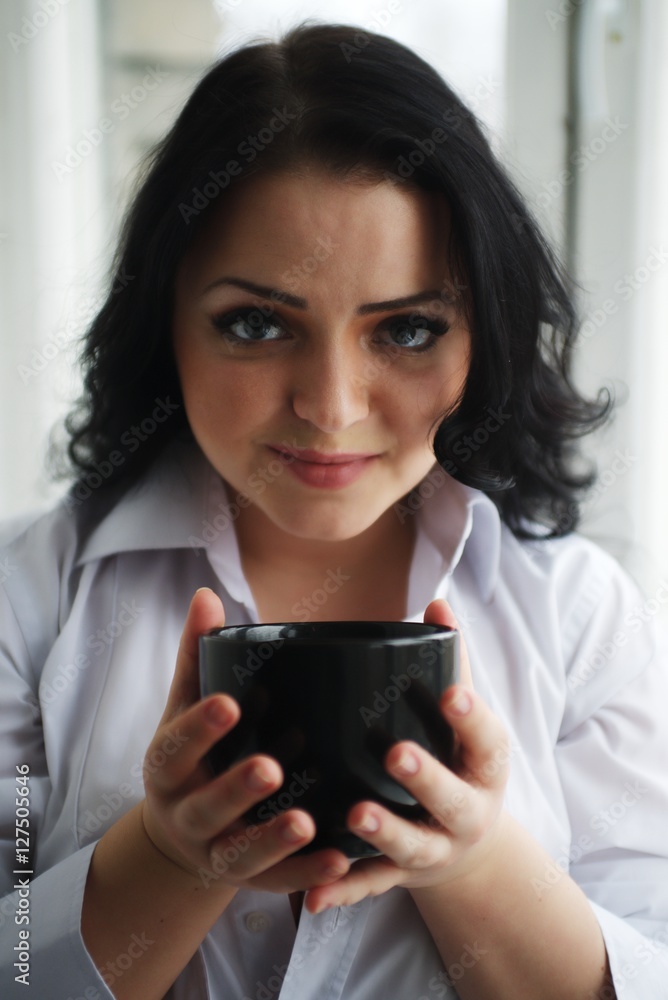 Portrait of young woman holding a cup of coffee. Portrait of young woman holding a cup of coffee.