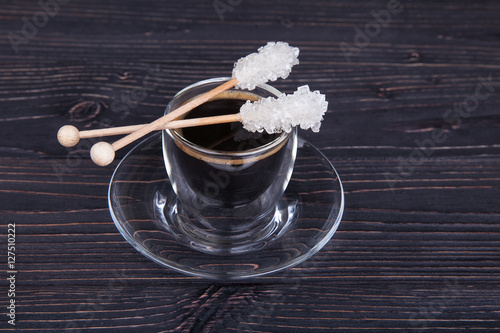 glass of coffee with a sugar crystalls sticks on a wooden backgr photo