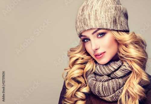 trendy warm winter - beautiful young blonde woman in gray wool winter hat and scarf smiling . Portrait of beauty winter girl in knitted woolen clothing hat and Snood . 