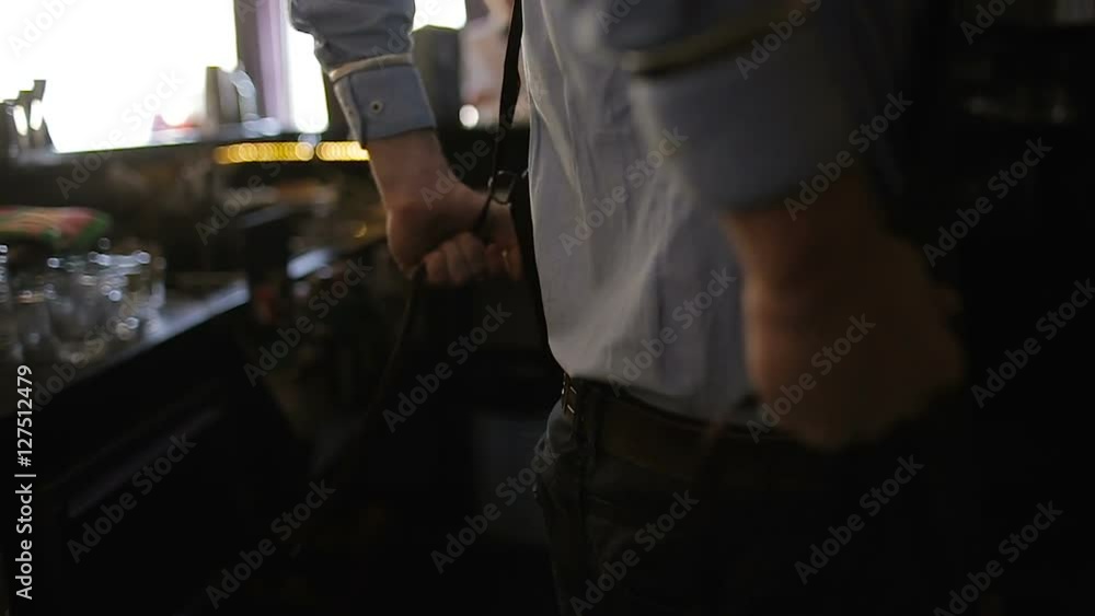 The bartender in the restaurant dresses an apron The bartender in the restaurant dresses an apron