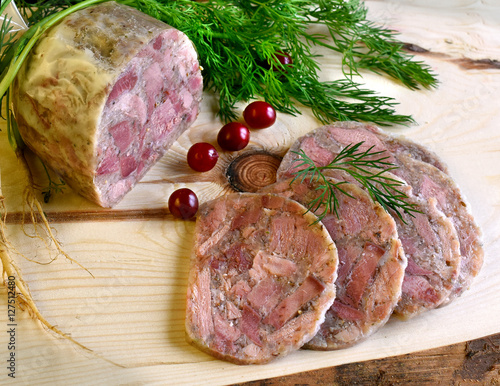 Homemade headcheese with dill and cranberries on a wooden board photo