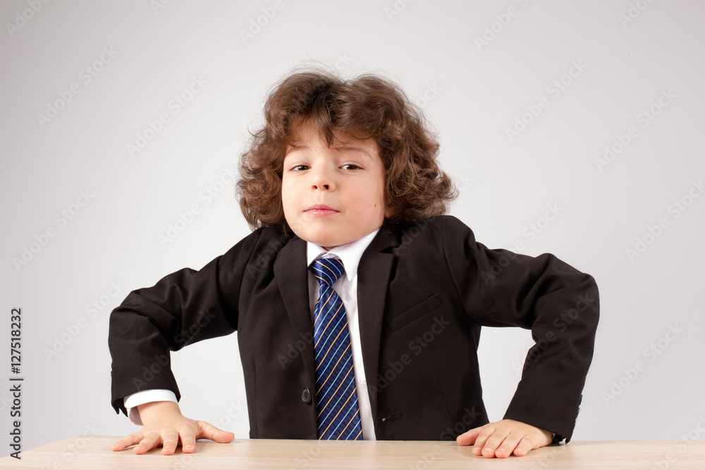 Business curly boy stands up from the table. Gray background. Close-up. Business curly boy stands up from the table. Gray background. Close-up.