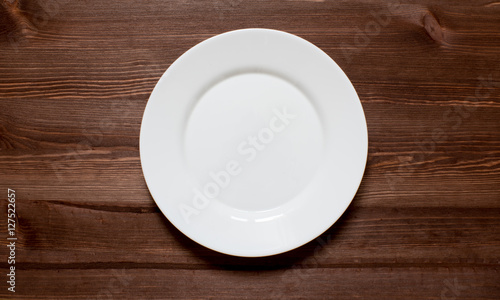 White round plate on a wooden background.