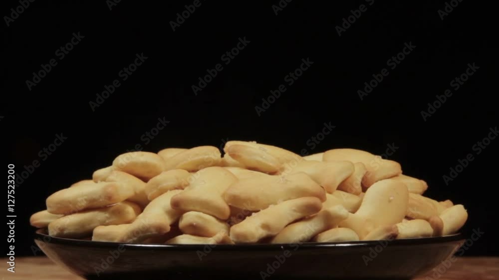 Cookies cracker rotate on a black plate in black background. Cookies cracker rotate on a black plate in black background.