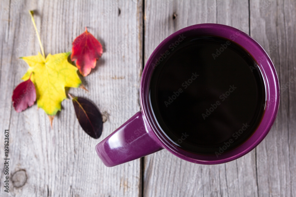 Cup of coffee surounded by red, purple and yellow fall leaves Cup of coffee surounded by red, purple and yellow fall leaves