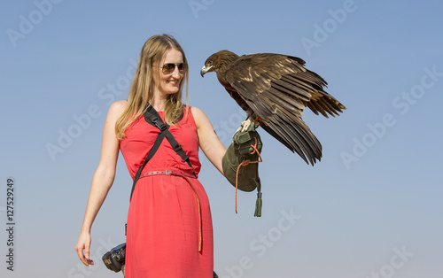 A woman with a greater spotted eagle in a deseert near Dubai photo