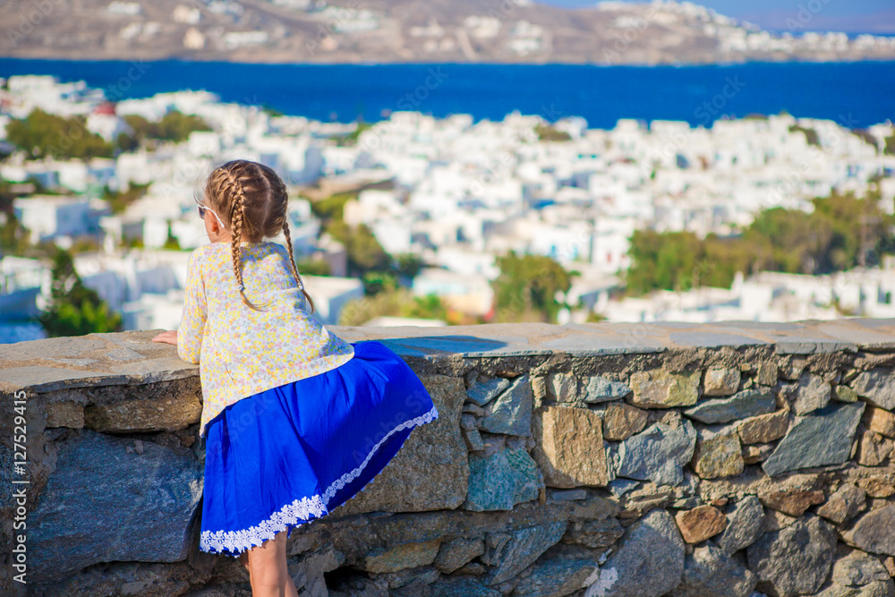 Fototapeta premium Adorable little girl in Mykonos town background amazing view of traditional white houses