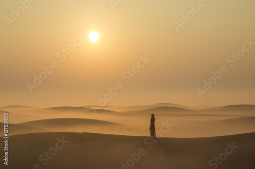 a woman in a desert at sunrise near Dubai