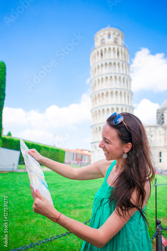 Young happy girl with toristic map on travel to Pisa. Tourist traveling visiting The Leaning Tower of Pisa. photo