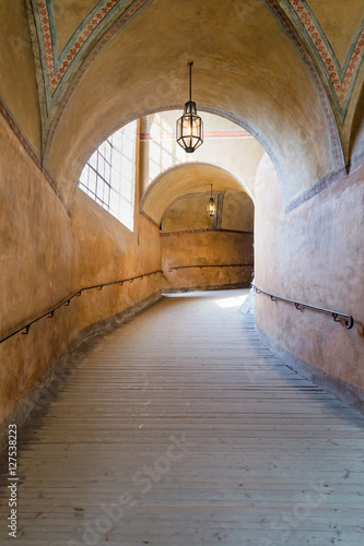 An arched tunnel with wooden floor in an old castle with sunlight from the window, Czech © rostovdriver