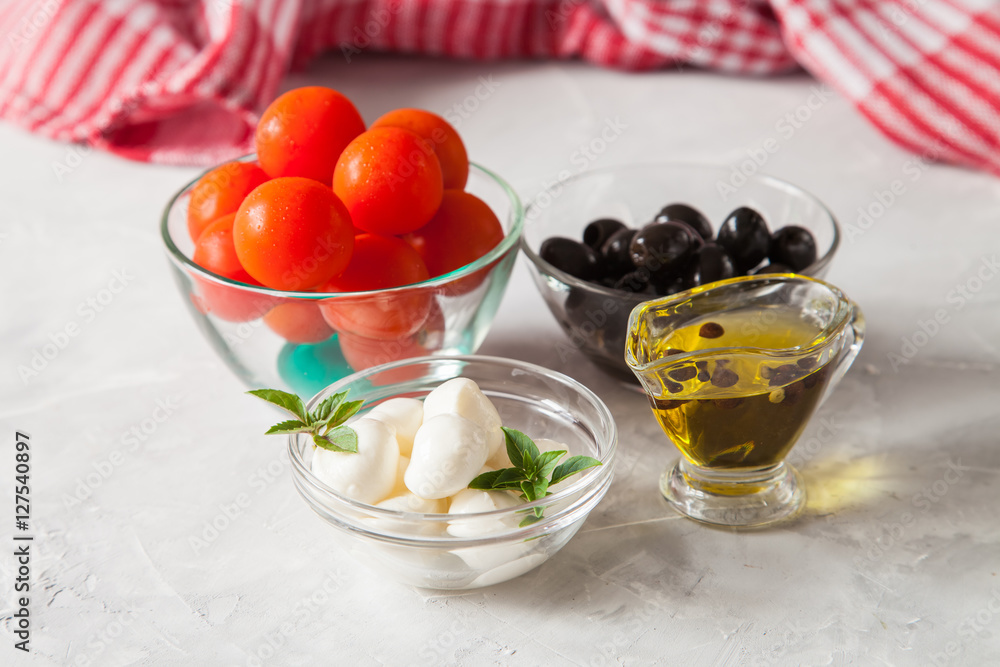 ingredients for salad - cheese, a tomato, olives and oil. selective focus ingredients for salad - cheese, a tomato, olives and oil. selective focus