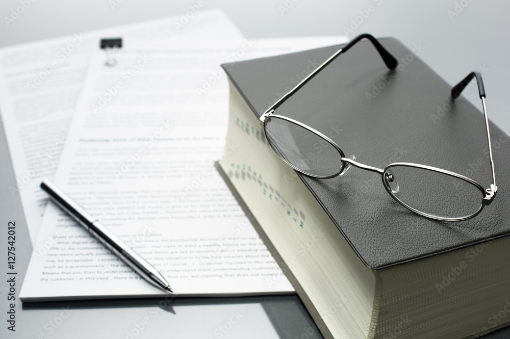 Reading and checking documents with a dictionary. Documents, dictionary, glasses and pen on gray reflection background.
Reading and checking documents with a dictionary. Documents, dictionary, glasses and pen on gray reflection background.