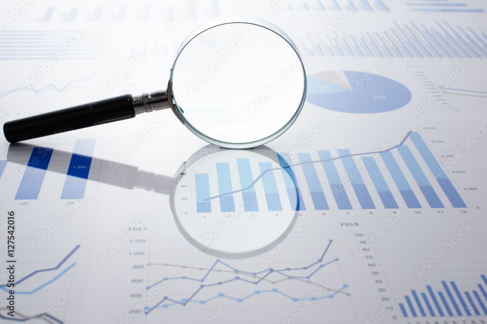 Fototapeta premium Accounting data, charts and magnifying glass. Many charts and graphs. Reflection light and flare. 