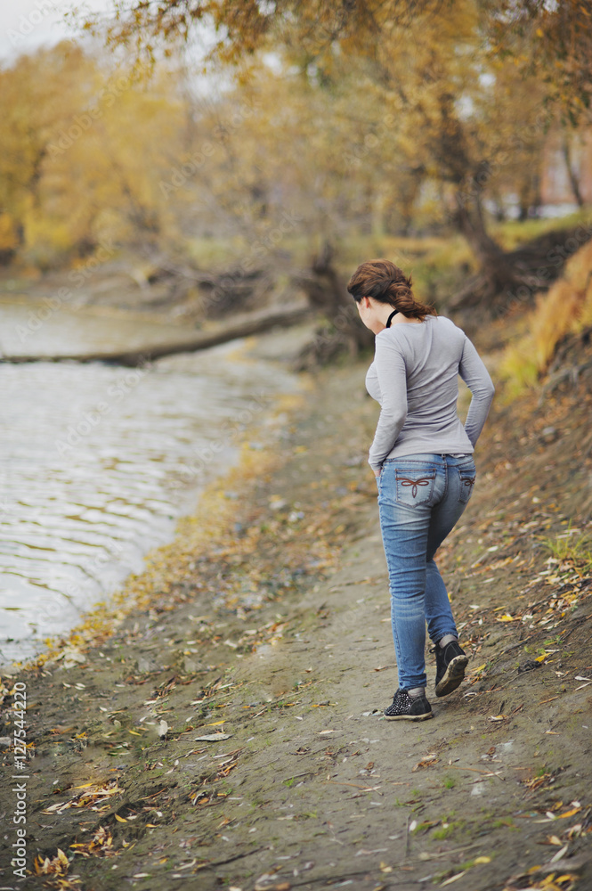 Girl goes along the coast. Rear view. Autumn, the wind blows. Girl goes along the coast. Rear view. Autumn, the wind blows.