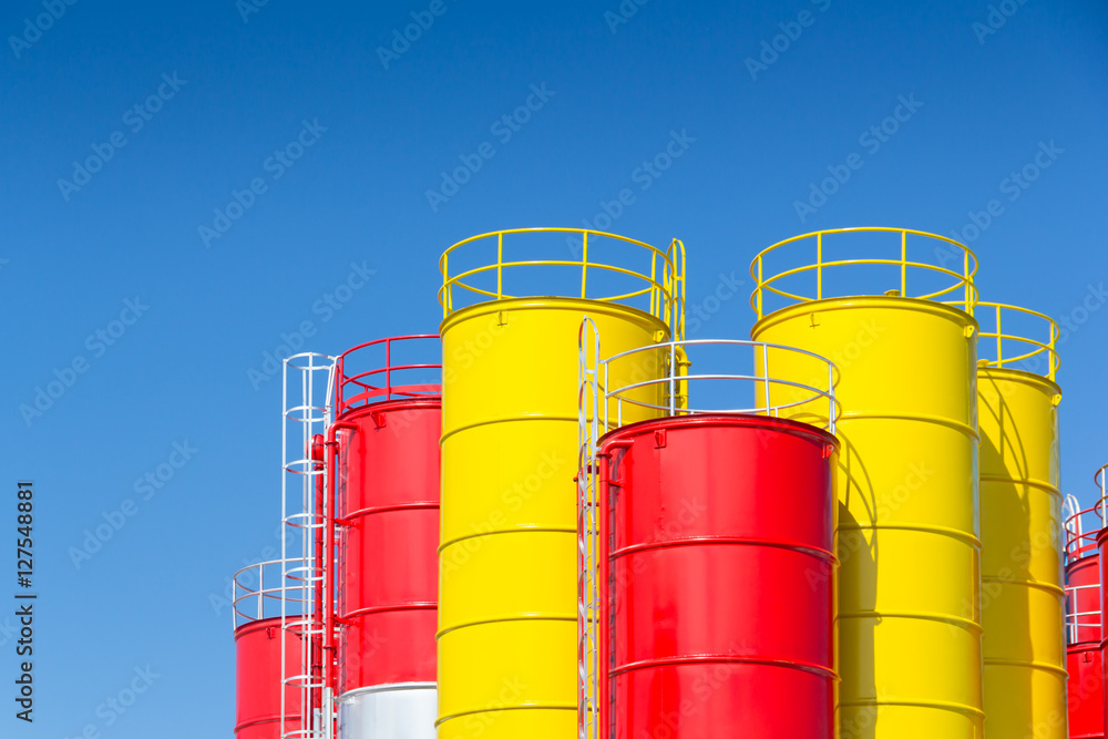 yellow and red steel silo against blue sky, metal silos for concrete mix process plant.. yellow and red steel silo against blue sky, metal silos for concrete mix process plant..