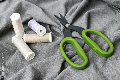 Threads and scissors on grey fabric.