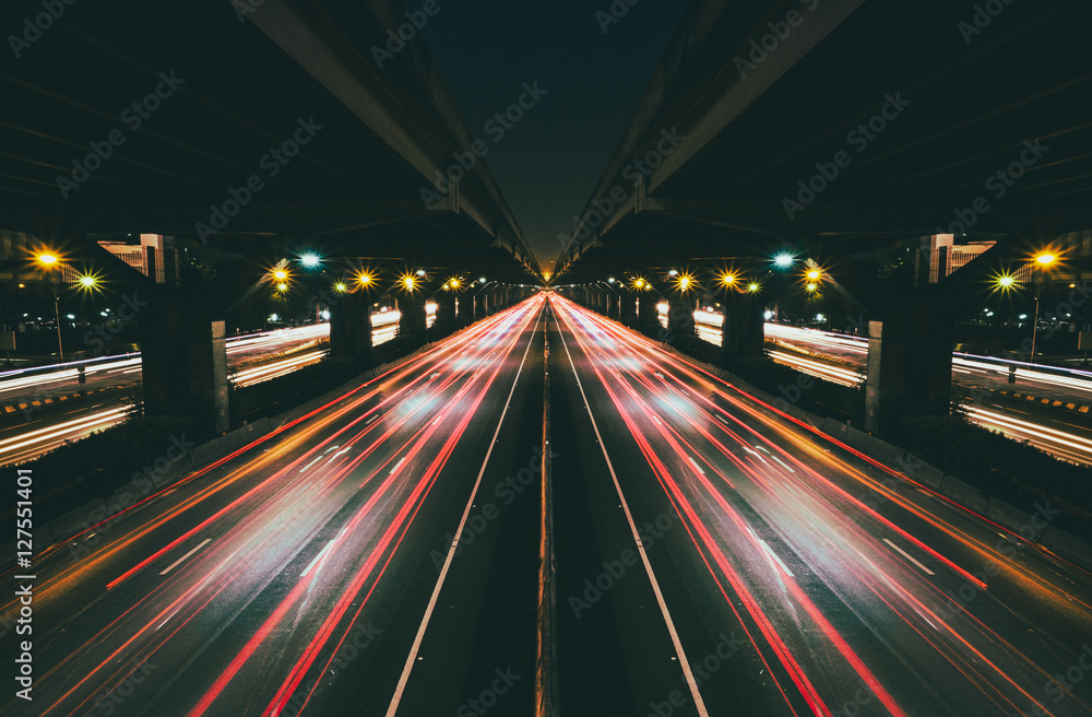 Fast moving traffic with red light trails on black asphalt motorway