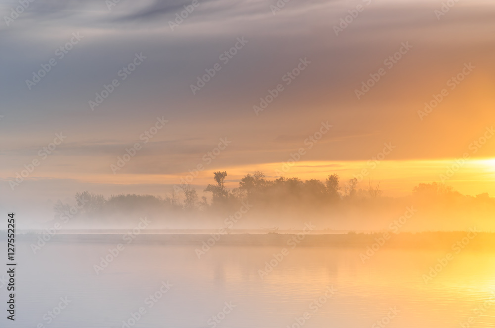 Orange sunrise over a misty wild river