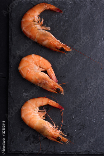 Top view of fresh shrimps on black stone slate with copyspace. Seafood ingredients preparation.