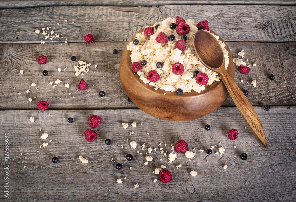 Cottage cheese with fresh raspberries and blueberries on wooden